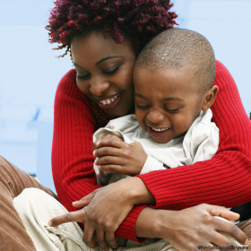 Young African-American mother hugs her laughing two-year-old son