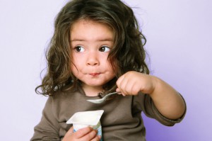 two-year-old girl enjoying a cup of yogurt