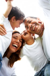Latino/Hispanic family with pre-school children laughing & hugging each other