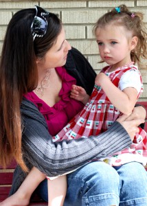 young mother chatting with slightly upset three-year-old outside pre-school
