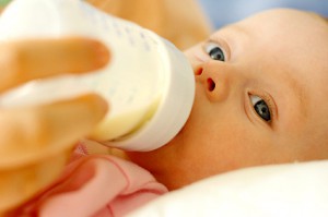 Close-up of two-month-old baby drinking formula from a bottle.