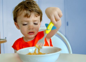 three-year-old boy unhappily picking at his mac-and-cheese