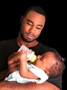 young African-American father bottle-feeding his baby daughter