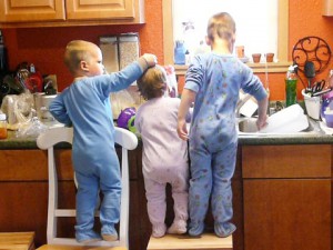 pre-school-aged siblings work together to wash the family's dishes