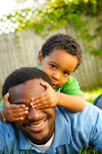 African-American father and three-year-old son play peek-a-boo