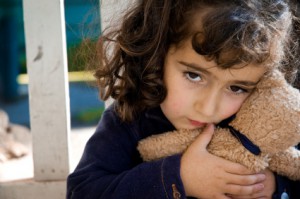 pensive three-year-old girl clutching her teddy bear